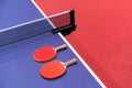 Two pingpong table tennis rackets for playing are laid on next to net on the blue table. This is one of ping pong sports equipment