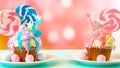 Two pink and blue novelty cupcakes decorated with candy and large lollipops.
