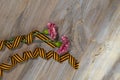 Two pink carnations, Saint George ribbon on a wooden surface