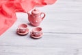 Two pink ceramic tea cups and a teapot on the table. Invitation card Royalty Free Stock Photo