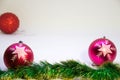 Two pink festive balls in focus with a red ball in the corner out of focus