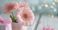 two pink flowers in a vase and gifts on white wood Royalty Free Stock Photo