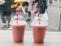 Two pink fruit milk cocktails in plastic cups with white-red tubes spiral pattern for milkshakes, cocktails, juices stand on table Royalty Free Stock Photo