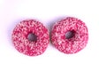 Two pink glazed donuts laying next to each  other on white background Royalty Free Stock Photo