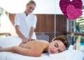 Two pink heart icons against female masseur massaging young woman lying in a massage parlor Royalty Free Stock Photo