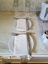 Two place settings are ready with plates, silverware, glasses, and a kettle in a light, neutral space Royalty Free Stock Photo