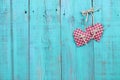 Two plaid country hearts hanging on antique teal blue wood door Royalty Free Stock Photo