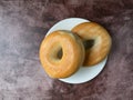 Two plain bagels on a white plate atop a red mottled countertop top view Royalty Free Stock Photo