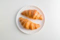 Two plain croissant on the plate, white table background Royalty Free Stock Photo