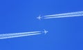 Two planes flying high in the sky meet, leaving streaks Royalty Free Stock Photo