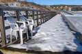 Two plastic chairs standing on a snow covered wooden jetty with part of Ornskoldsvik town in background