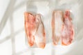 Two plastic containers filled with frozen red snapper fillets being held and displayed in bright lighting Royalty Free Stock Photo