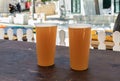 Two plastic half-liter glasses with beer stand on wooden table on the main pedestrian HaMeyasdim street in Zikhron Yaakov Royalty Free Stock Photo