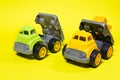 Two plastic trucks on a yellow background. Toys for a boy toy store