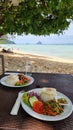 Two plates of delicious food are set on a table near the beach, with the ocean waves gently crashing in the background Royalty Free Stock Photo