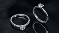Two platinum diamond rings sits on a shiny black glass surface. heart shaped diamond rings design with 3d Royalty Free Stock Photo