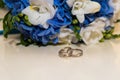 Two platinum wedding rings lie around the bride's bouquet of blue and white flowers. Royalty Free Stock Photo