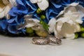 Two platinum wedding rings lie bouquet of blue and white flowers. Royalty Free Stock Photo
