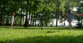 Two playful siblings kick football ball in city garden. Kids rest on sunny day