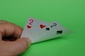 Two playing cards in fingers of hands on a green background Royalty Free Stock Photo