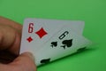 Two playing cards with a pair of sixes in fingers of hands on a green table Royalty Free Stock Photo