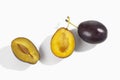 two plums one whole one halved on white background
