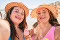 Two plus size overweight sisters twins women eating sweet ice cream at the beach on summer holidays Royalty Free Stock Photo