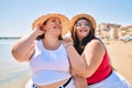 Two plus size overweight sisters twins women happy at the beach on summer holidays