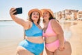 Two plus size overweight sisters twins women happy taking a selfie picture at the beach on summer holidays Royalty Free Stock Photo