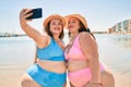 Two plus size overweight sisters twins women happy taking a selfie picture at the beach on summer holidays Royalty Free Stock Photo