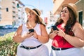 Two plus size overweight sisters twins women with smartphone outdoors on a sunny day
