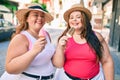 Two plus size overweight sisters twins women smiling eating an ice cream outdoors Royalty Free Stock Photo