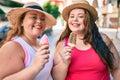 Two plus size overweight sisters twins women smiling eating an ice cream outdoors Royalty Free Stock Photo
