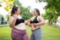 Two plus size woman share a moment during their workout in green park, embodying joy and fitness.