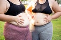 Two plus size woman share a moment during their workout in green park, embodying joy and fitness.