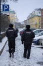 Two police officers patrol snowy streets in Russia. A man walks in front