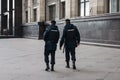 Two policemen walk around the city in the direction from the viewer, we see their backs with the inscription in Russian -