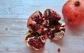 Two pomegranates, red fruit, pomegranates on a light wooden background, an open pomegranate and juicy red pomegranate seeds