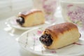 Two poppy buns in white romantic saucers on a white table. Tea time. Side view