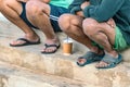 Two port workers taking a break sitting with sandals on their feet and having cold coffee in Heraklion, Greece