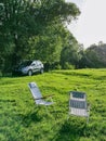 two portables chairs at green field suv car on background Royalty Free Stock Photo