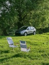 two portables chairs at green field suv car on background