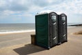 Two Portaloo cubicles on seafront promenade with the ocean in the background.