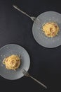 Two portions of Spaghetti traditional Italian dish spaghetti carbonara with bacon in a cream sauce in a plate over dark background