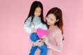 Two portrait beautiful cute asia child girl and woman on pink background with red heart sign holding in hand, valentine day in lov Royalty Free Stock Photo