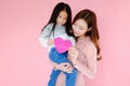 Two portrait beautiful cute asia child girl and woman on pink background with red heart sign holding in hand, valentine day in lov Royalty Free Stock Photo