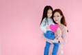 Two portrait beautiful cute asia child girl and woman on pink background with red heart sign holding in hand, valentine day in lov Royalty Free Stock Photo