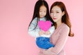 Two portrait beautiful cute asia child girl and woman on pink background with red heart sign holding in hand, valentine day in lov Royalty Free Stock Photo