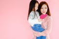 Two portrait beautiful cute asia child girl and woman on pink background with red heart sign holding in hand, valentine day in lov Royalty Free Stock Photo