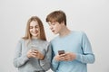 Two positive friends editing selfie to post it in social network. Friendly loving couple, girlfriend showing boyfriend Royalty Free Stock Photo